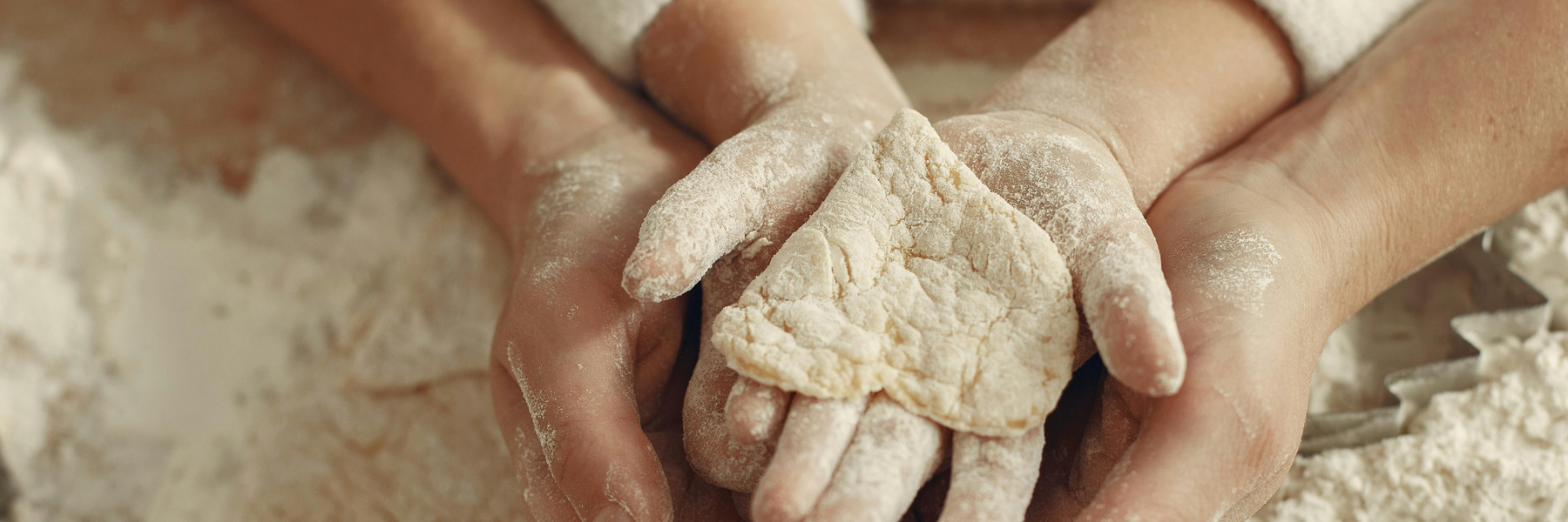adult and child hands holding handmade heart dough