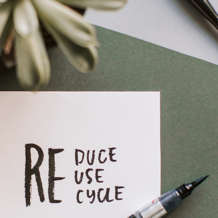 Green background with flower, pen and words Reduce Reuse Recycle