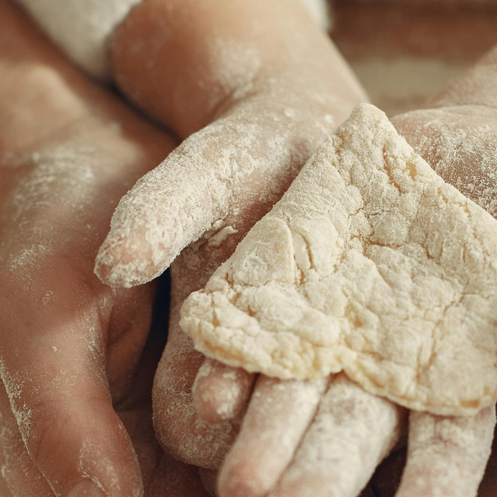 adult and child hands holding handmade heart dough